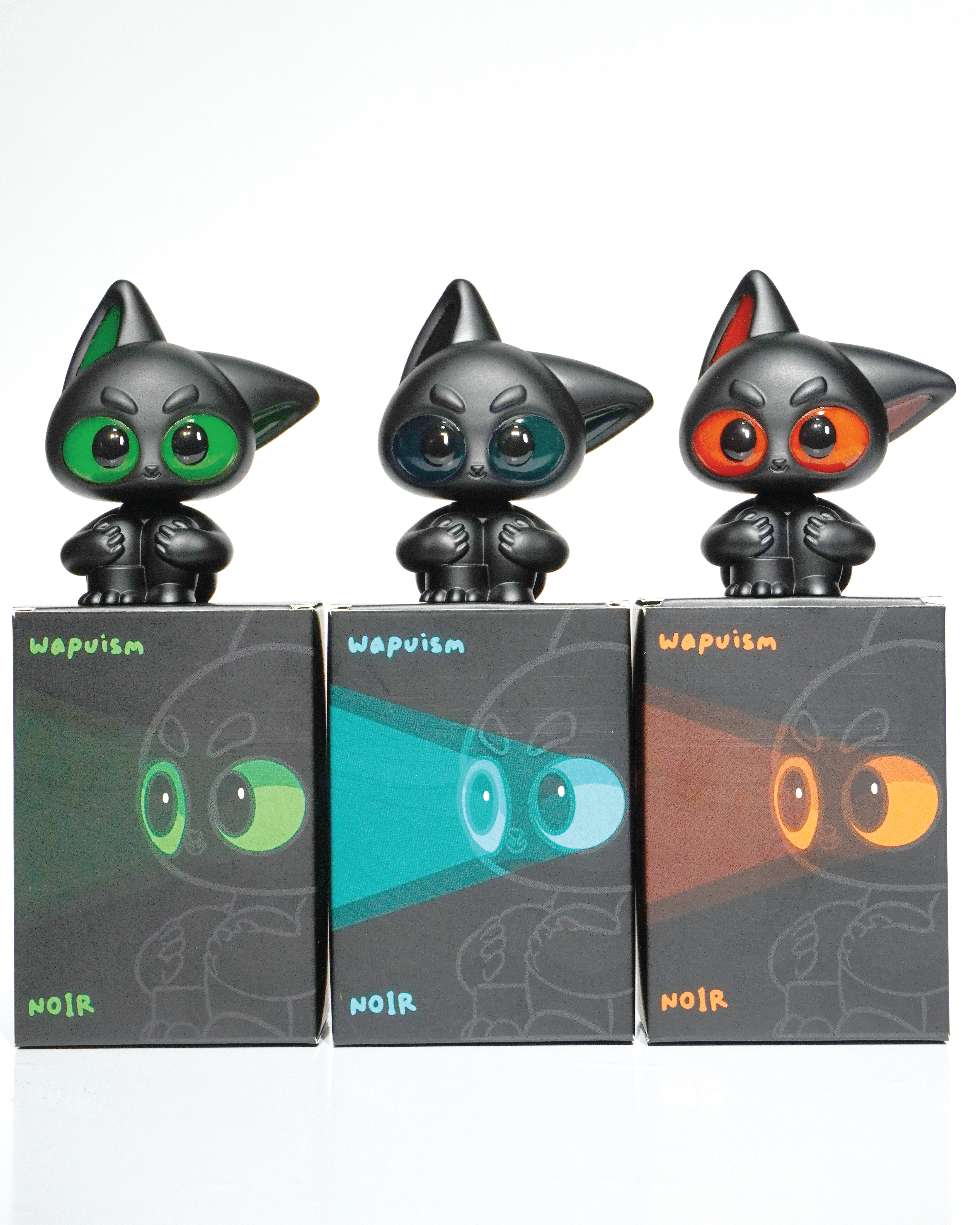 Noir by Wapu: Three black cat figures with neon glossy eyes in green, teal, and orange-red, each on a matching branded box.