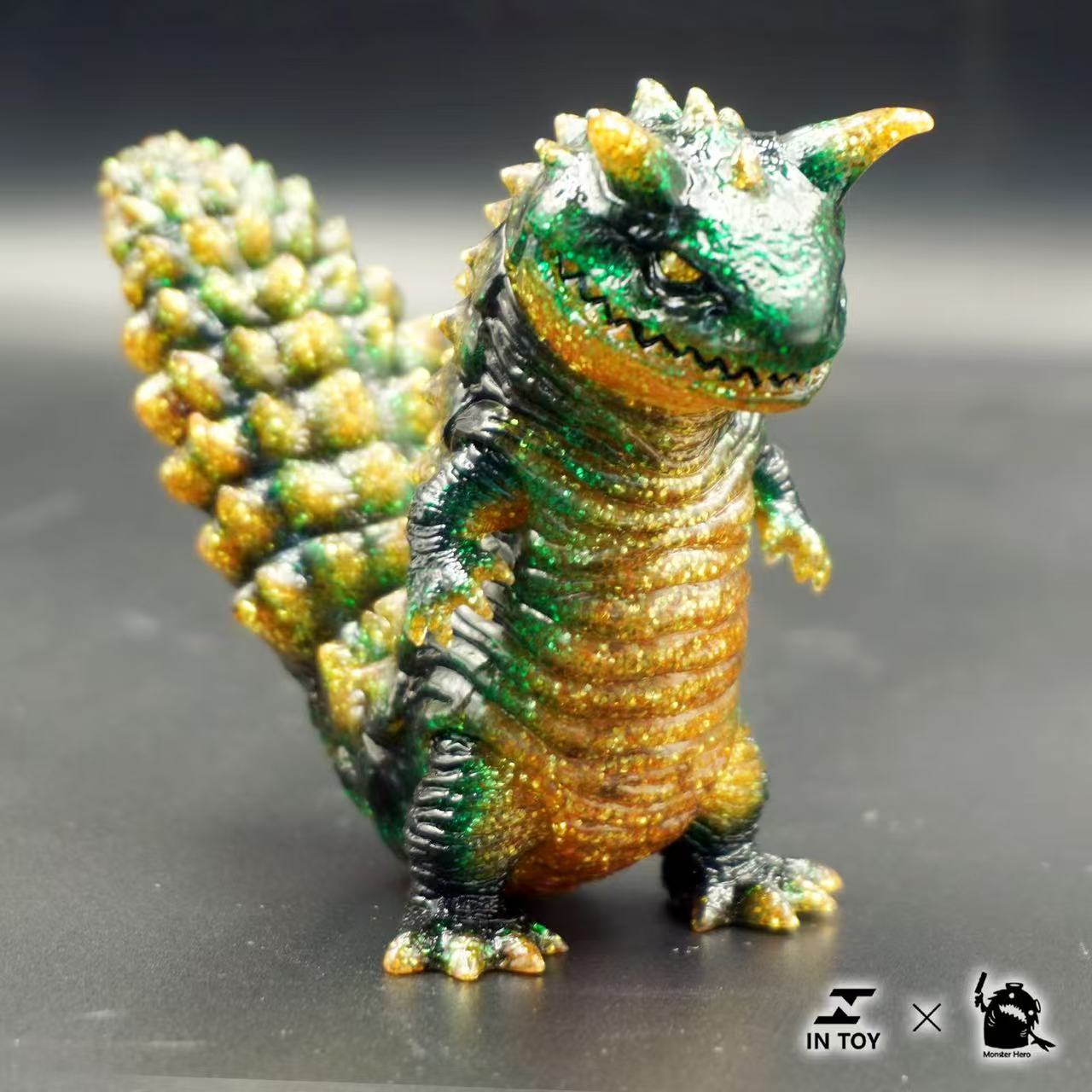 Mini Ultra Beast sofubi - brilliance .Ver: A designer vinyl kaiju figure with a textured tail, green and gold glitter; preorder for September 2025.