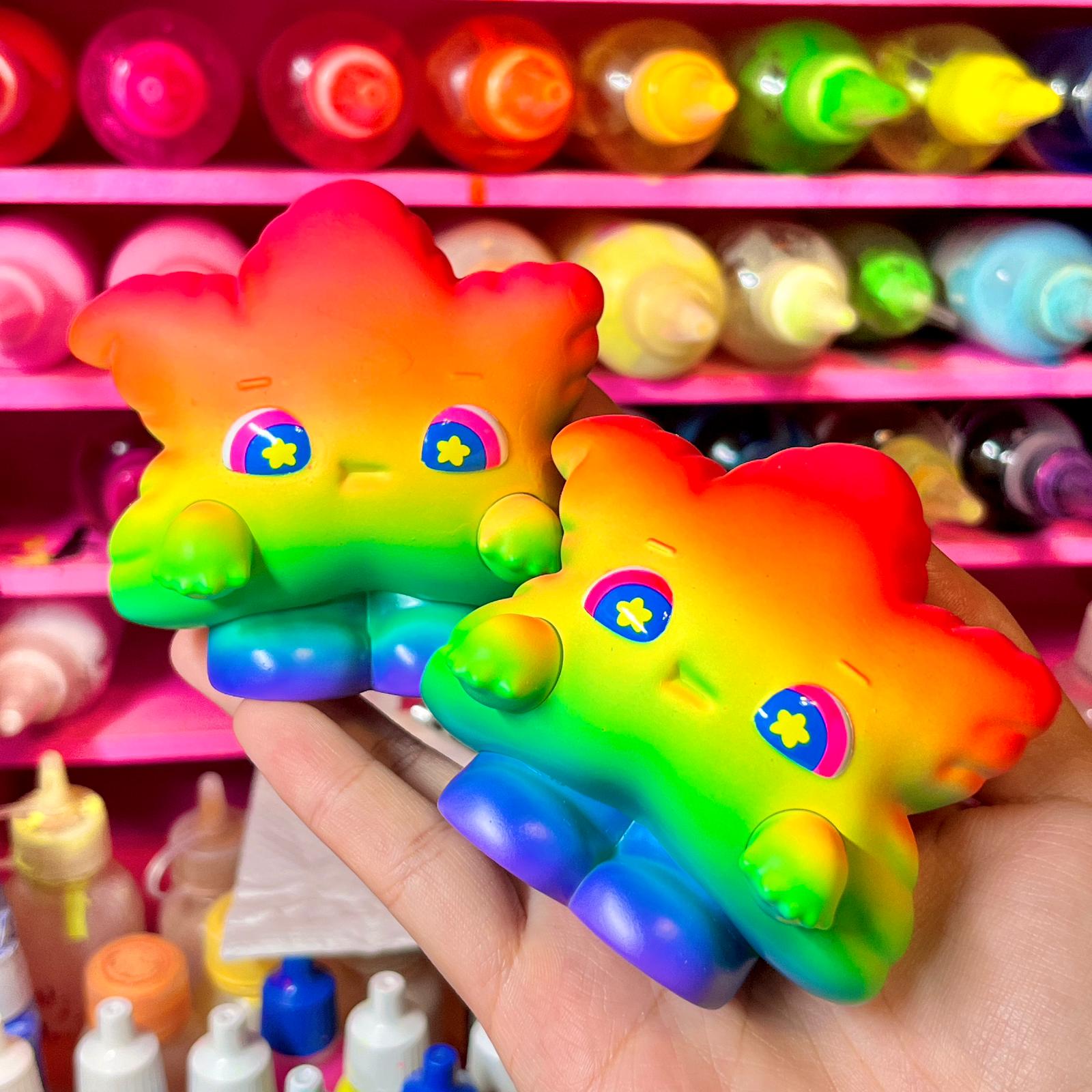 Rainbow Weee baby toy held in hand, with colorful flower and star details.