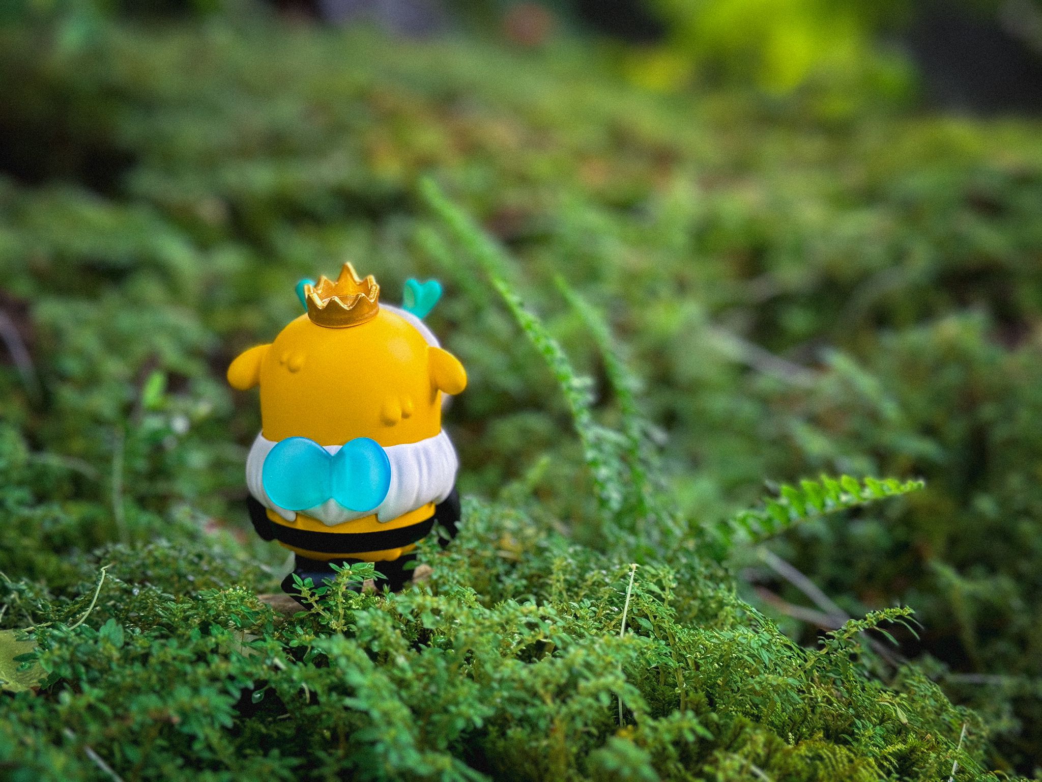 Little Muffinn: King Bee toy featuring a crown and blue bow, made of polyester resin, measuring 6-7 cm tall, displayed on grass.