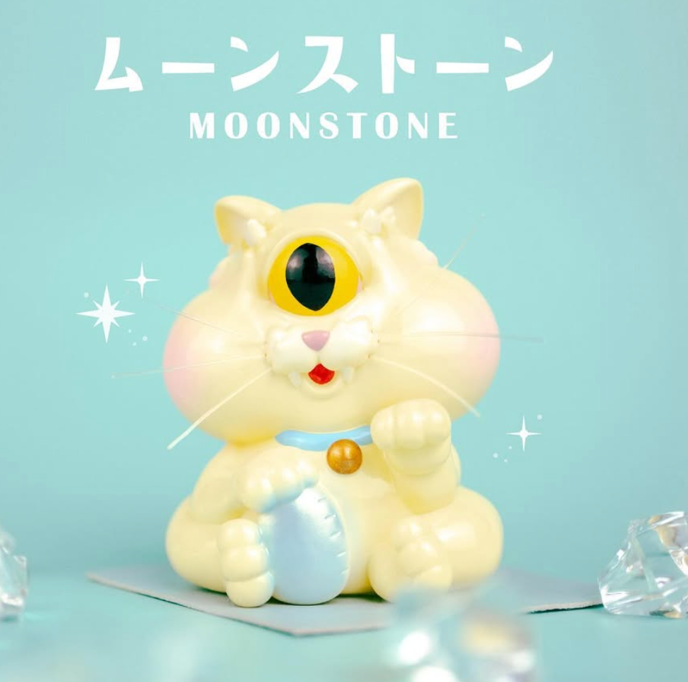 MOONSTONE by Boki x Kenneth Wan: A 9cm soft vinyl cyclops cat figurine, featuring a blue belly patch and collar, surrounded by sparkling gems.