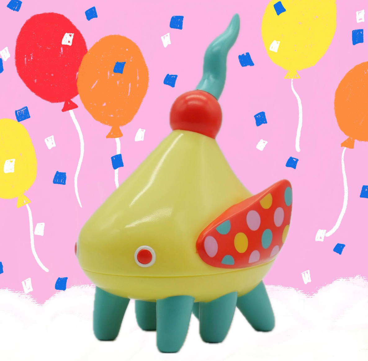 Sashimi - Baby Circus by Hanamusic: A whimsical, teardrop-shaped yellow sofubi toy with teal legs, a horn, and red wing-like panels, set against a festive backdrop.