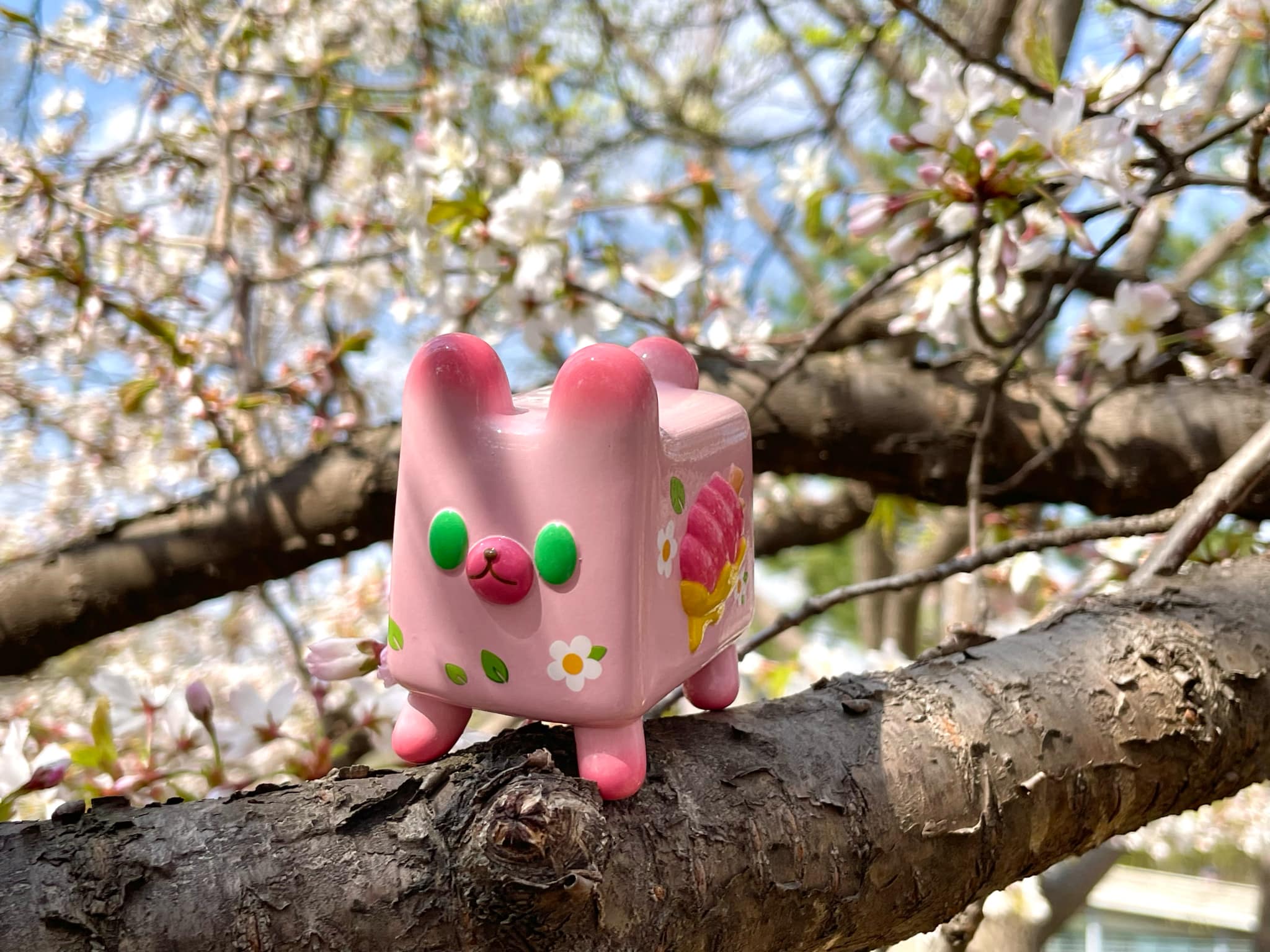 Box Bear - Sakura Spring Ver. by Rato Kim, a pink ceramic animal toy, perched on a tree branch, limited edition art piece from Strangecat Toys.