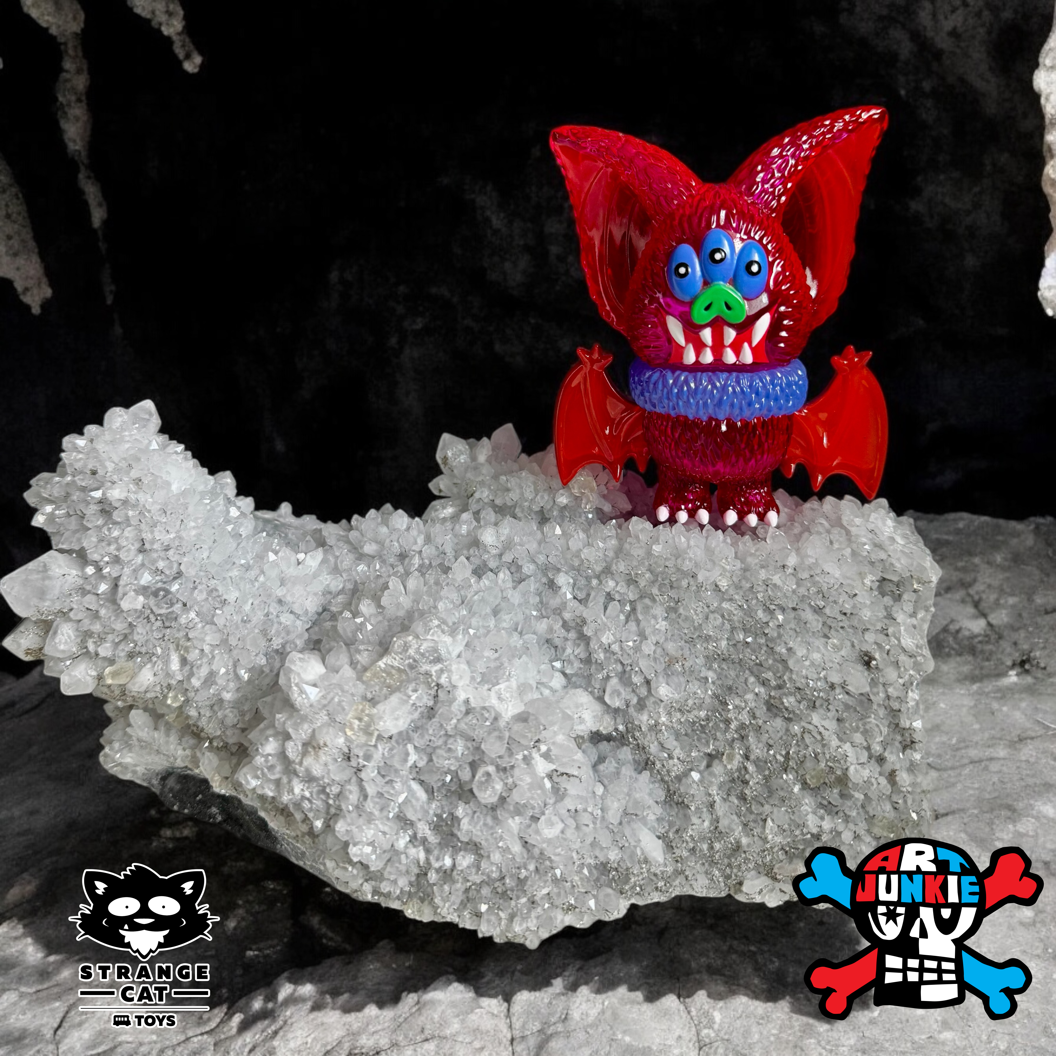 Beast Bat - Clear Pink by Art Junkie, a 4-inch soft vinyl toy with wings and teeth, displayed on a rock. Limited edition of 100 pieces.