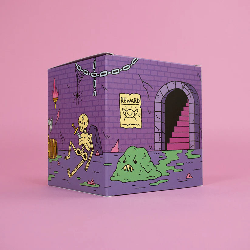 Wizard of Barge Dumpster Fire Vinyl Figure packaging featuring dungeon scene with slime, skeleton, and spider. Preorder collectible art toy by Strangecat Toys.