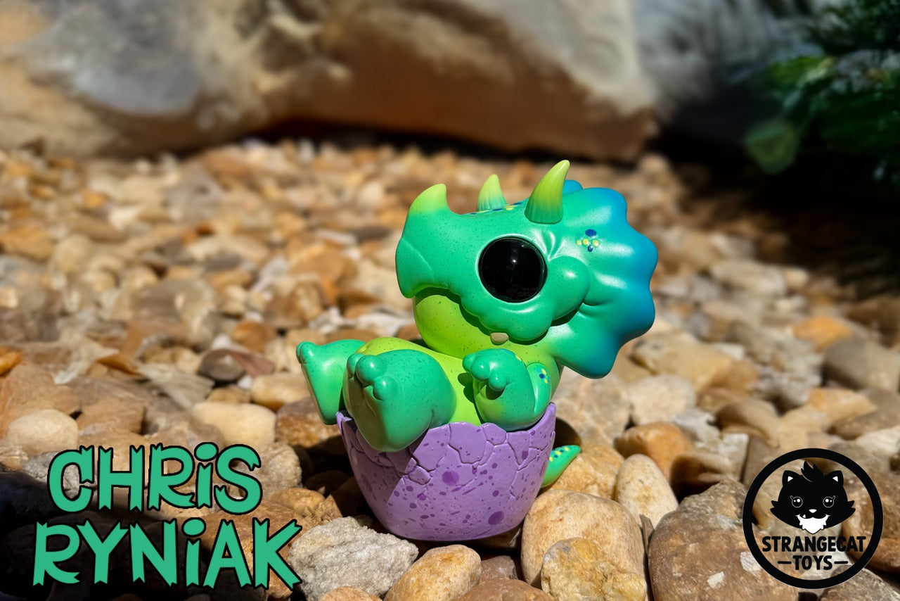 Seaside Eggtoof by Chris Ryniak - Preorder: A bright green baby dragon art-toy hatching from a purple eggshell, nestled on river stones. Limited edition of 75.