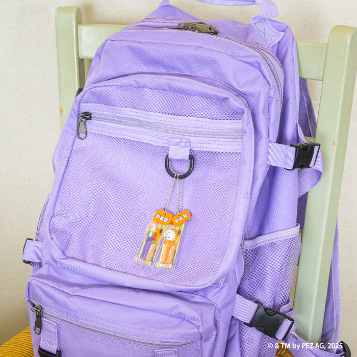 Lavender-purple backpack with a key-chain blister pack featuring two orange PEZ candy dispensers, part of the PEZ Ball Chain Mascot Halloween Ver. Gacha Series.