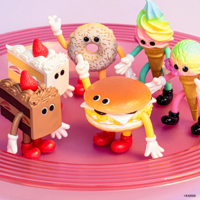 FLAVORS Figure Collection Vol.5 Gacha Series: whimsical anthropomorphic food-toy figures, including cake, doughnut, cheeseburger, and ice cream characters, posed on a pink platter.