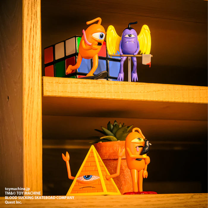 TOY MACHINE Collectibles Sect Gacha featuring quirky, one-eyed monster figures and a Rubik’s Cube on wooden shelves, available as random blind box toys.