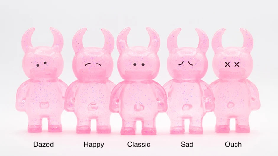 Five UAMOU CLEAR PINK GLITTER vinyl figures, 7cm tall, in varied expressions: Dazed, Happy, Classic, Sad, and Ouch. Made in Japan.
