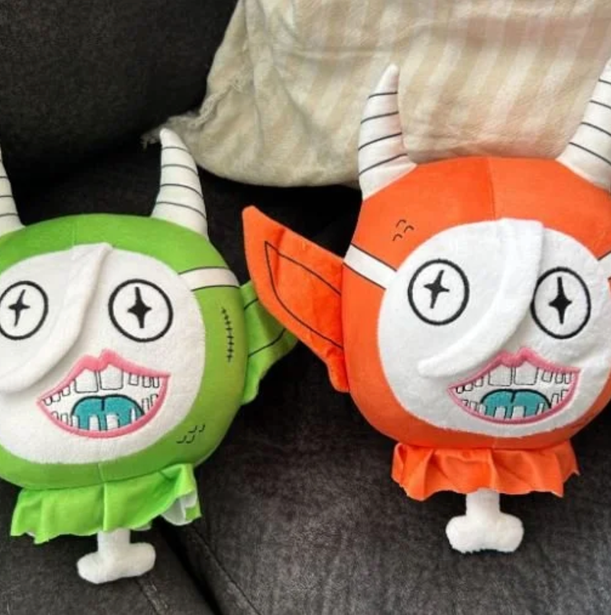 Gob Plush by Gloopy Goblin: Two horned plush monsters with starry eyes and toothy grins, featuring stitched details and ruffled collars, sitting on a couch.