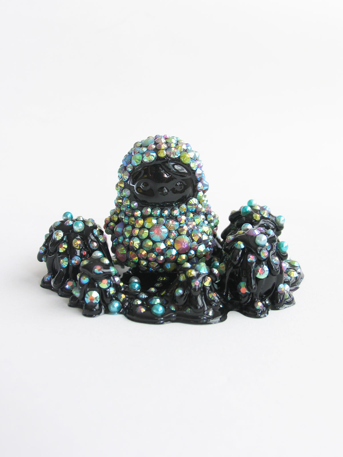 A black statue adorned with colorful crystals, beads, and jewelry, measuring 2 x 3 3/4 x 2 1/2.