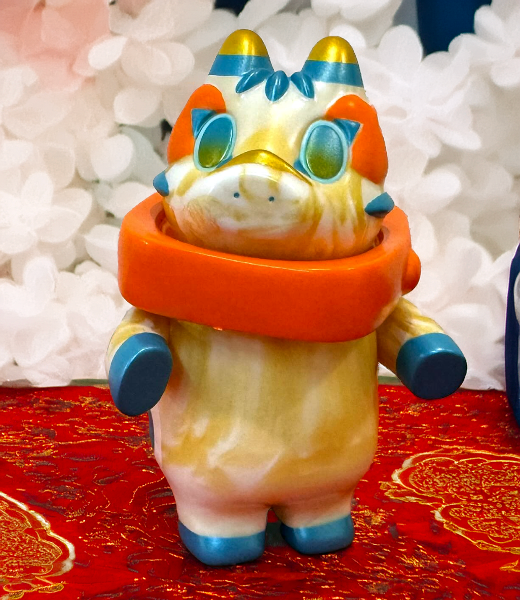 AKABEGON - White & Gold Marble 10th by Teresa Chiba: A 12cm sofubi art-toy with marbled cream-orange body, metallic blue accents, and oversized oval eyes.