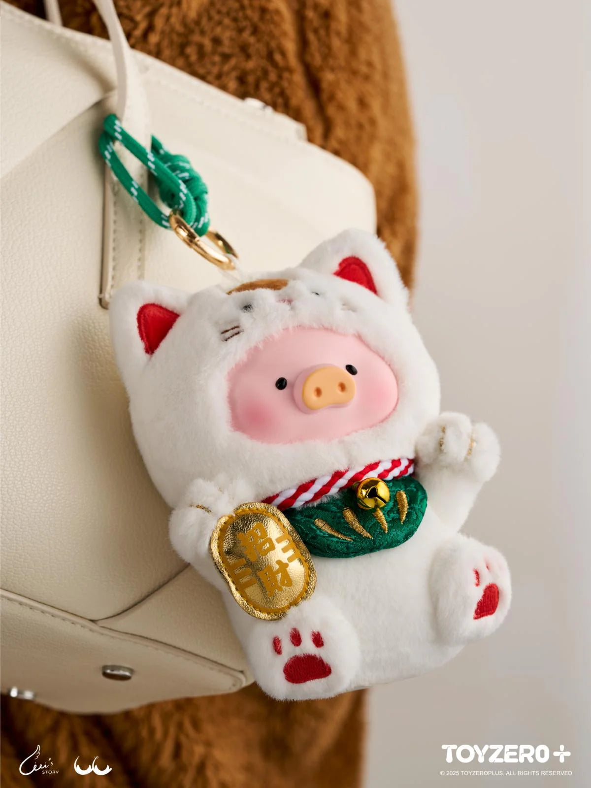 LuLu the Piggy 'Lucky Meow On My Hand' keychain, a plush piglet in a maneki-neko costume, hangs from a handbag, exuding charm and luck.