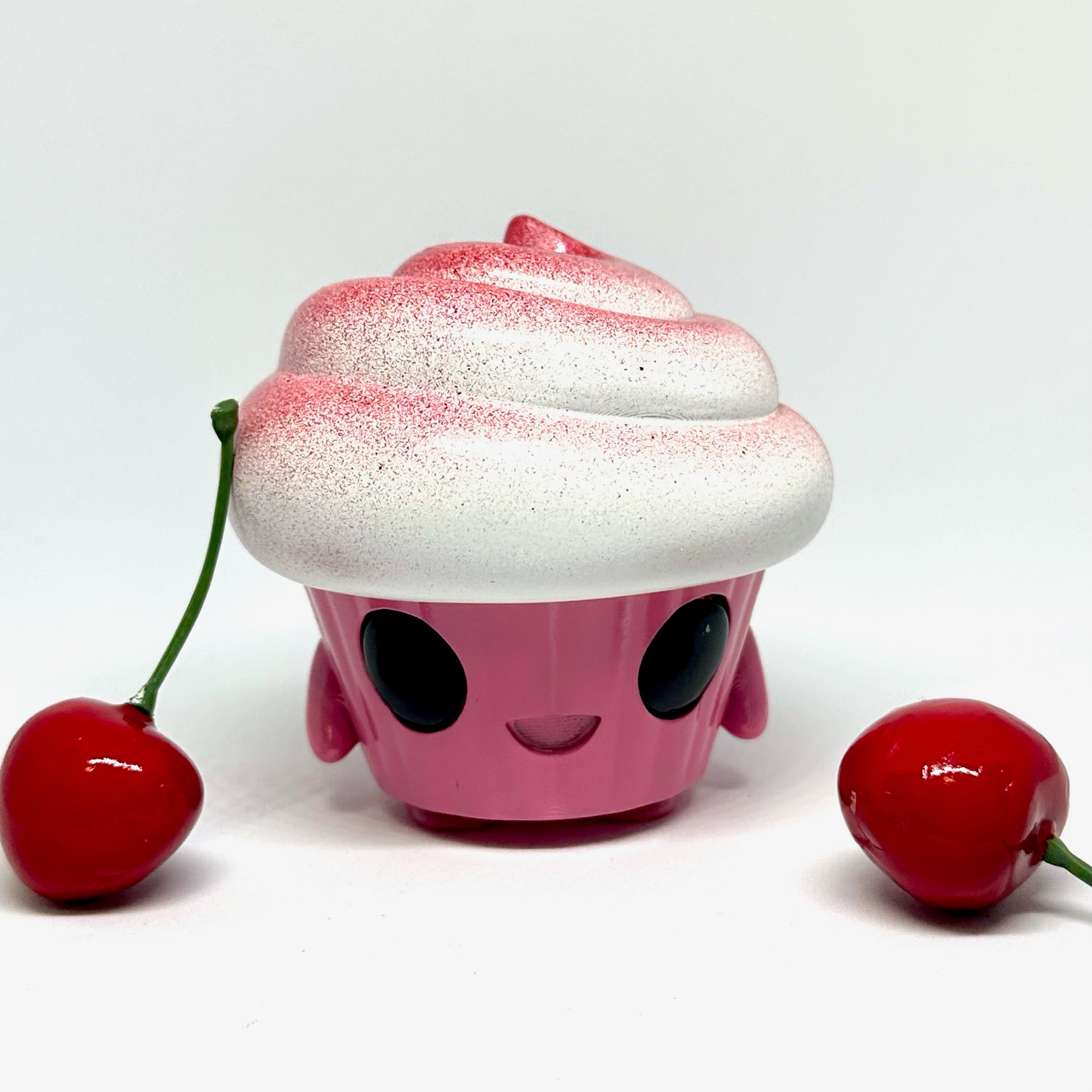 Toy cupcake with cherry, face, and stem, close-up of red pepper and fruit.