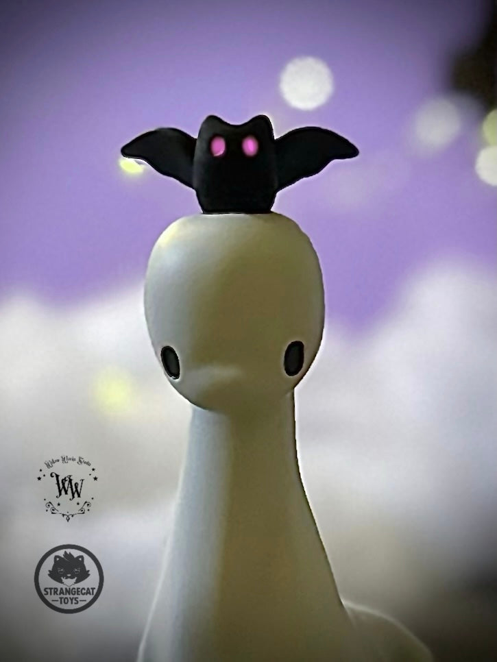 Ghost Dino by Willow Works, featuring a matte-white figure with black eyes and a tiny bat-like companion, limited edition collectible from StrangeCat Toys.