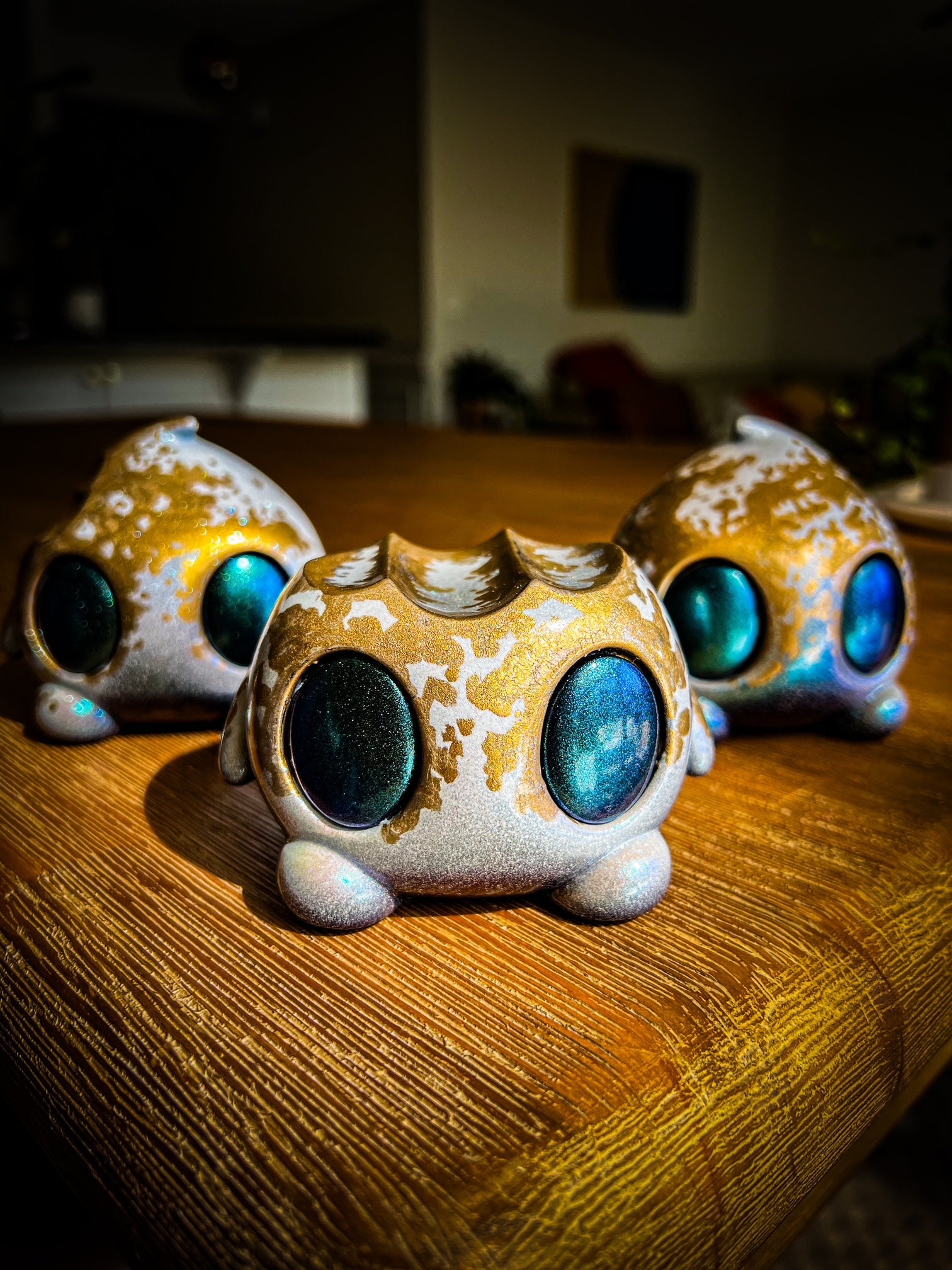 Figurines titled Bite Me - Bites by Mecha Panda, showcasing unique mixed media designs with distinct blue eyes, arranged on a table.