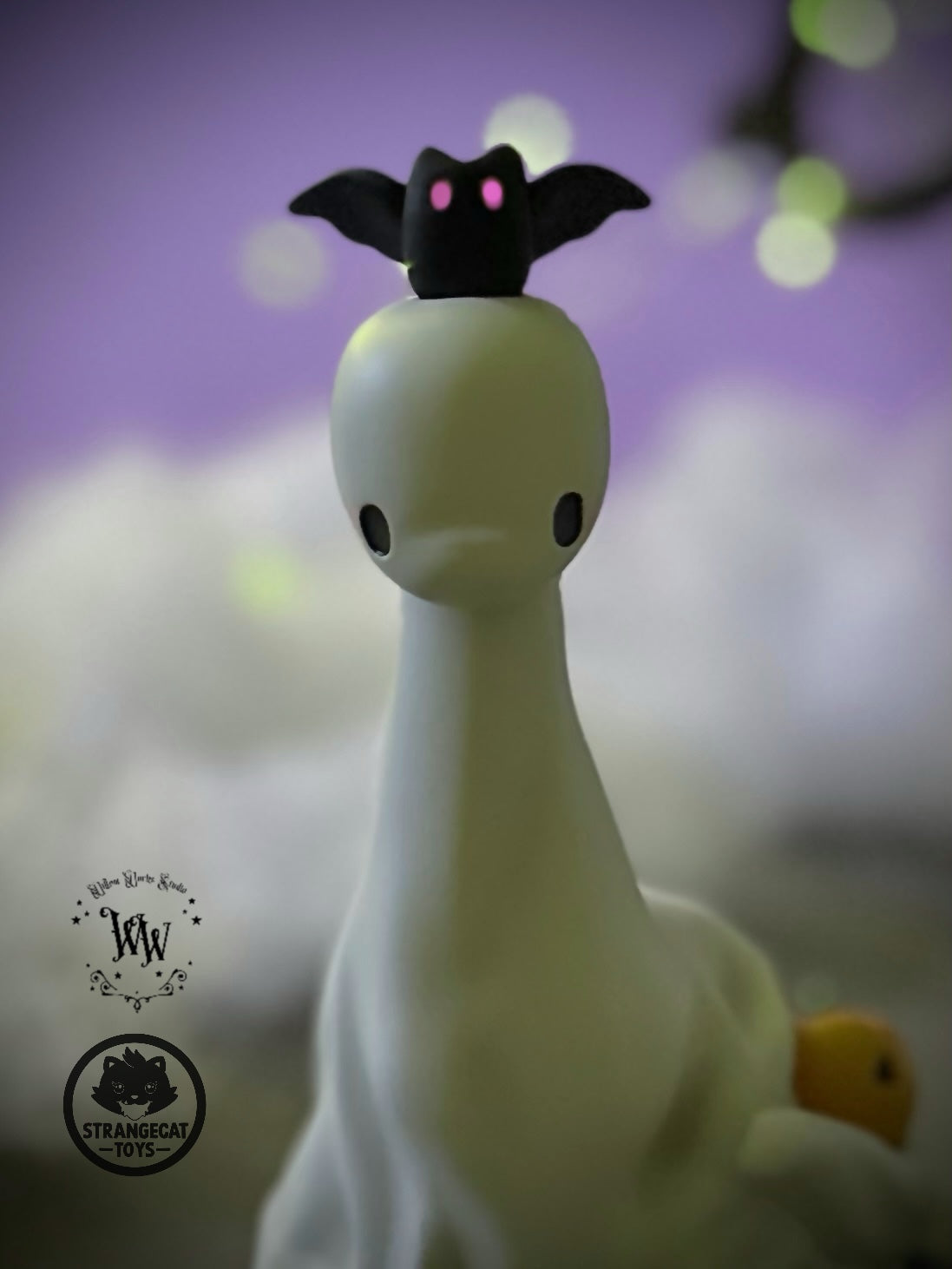 Ghost Dino by Willow Works: A 4 white ghost figurine with a melting base, black eyes, and a black bat atop. Limited edition of 75.