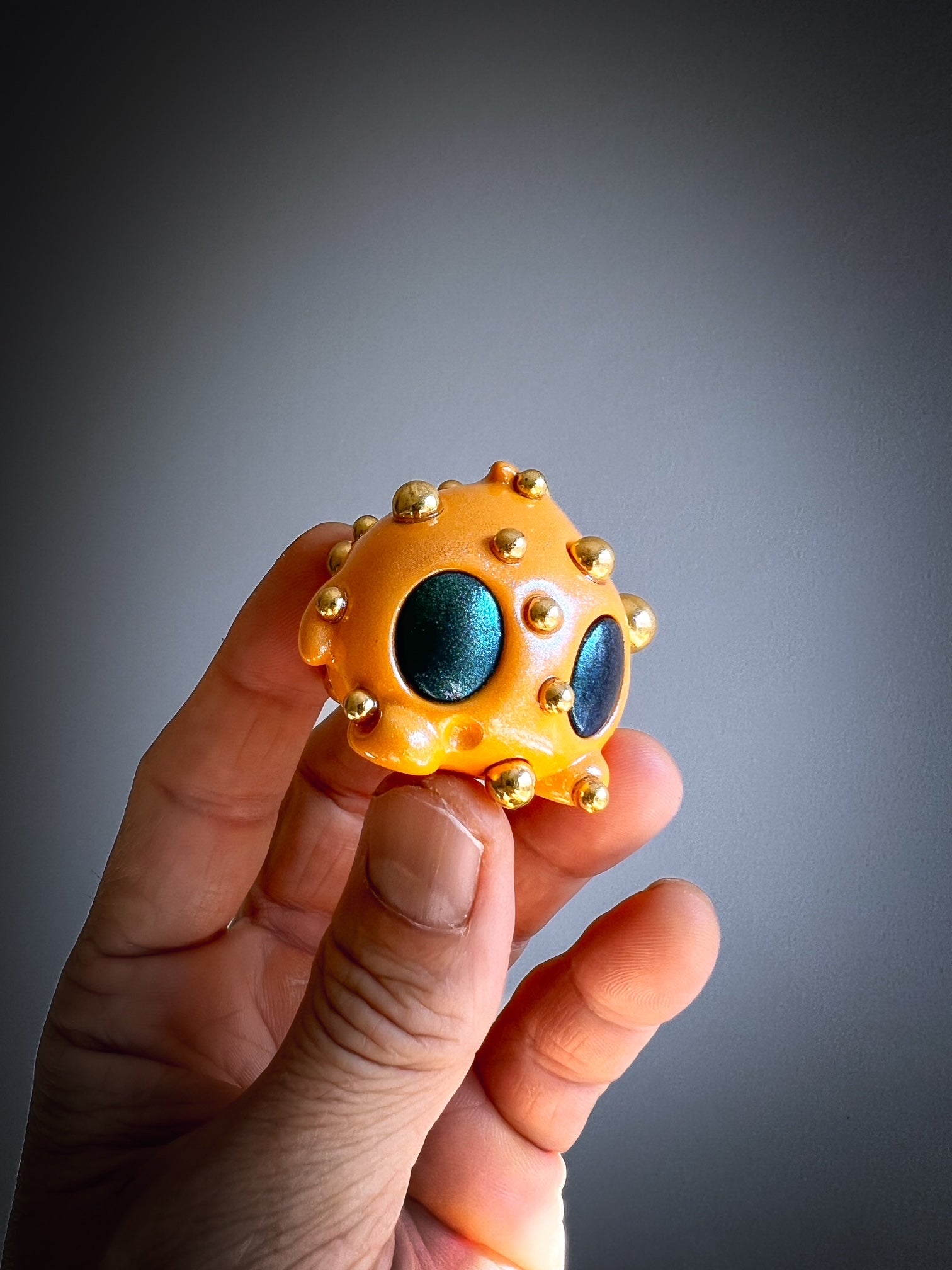Hand holding Bite Me - Bites by Mecha Panda, a unique mixed-media art toy featuring intricate blue and gold dot detailing.
