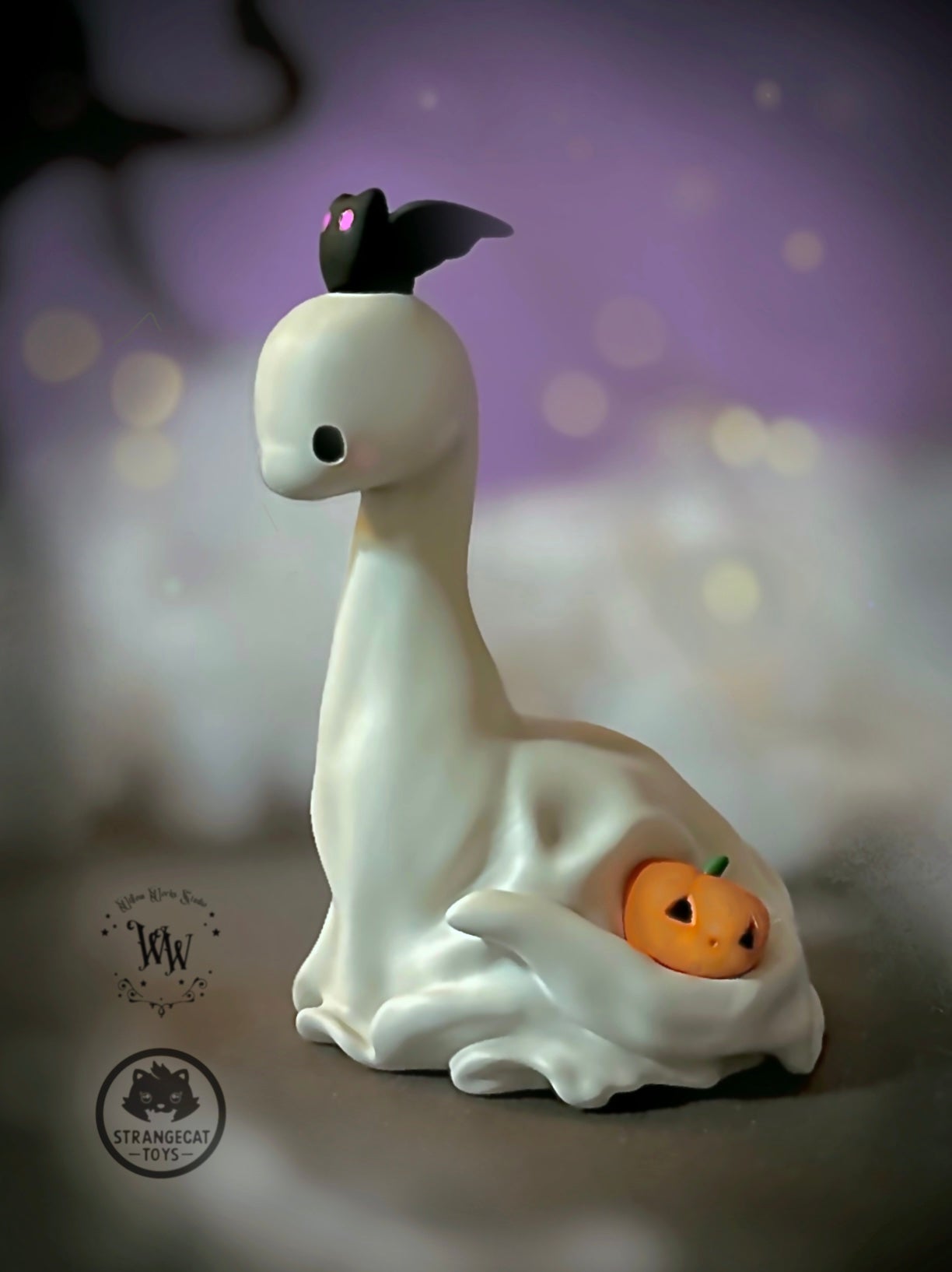 Ghost Dino by Willow Works: A small, white ghost figurine with a bat and jack-o’-lantern, made of high-grade resin. Limited edition, 4 inches tall.