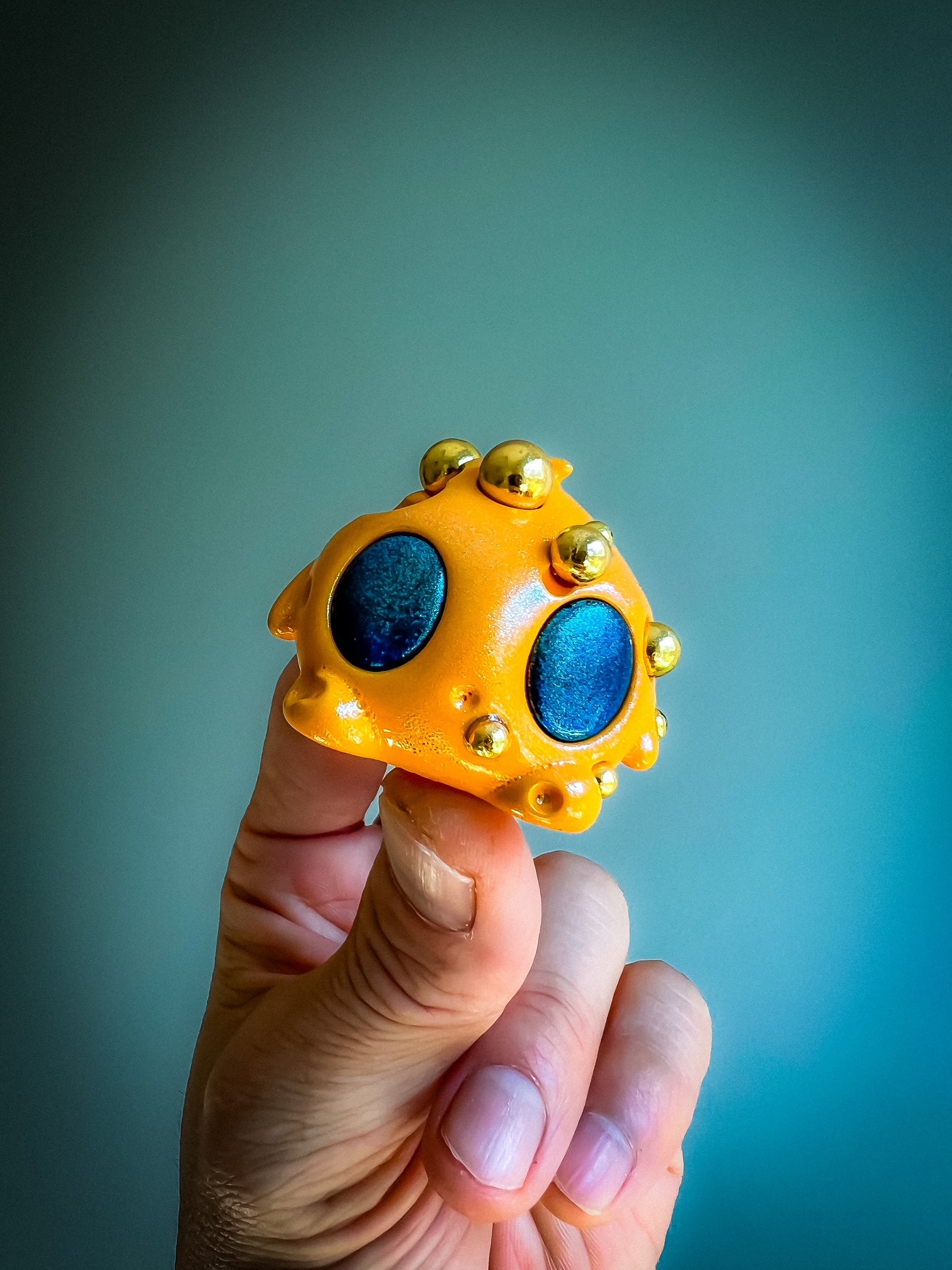 Hand holding Bite Me - Bites by Mecha Panda, a mixed media art toy from Strangecat Toys, featuring unique yellow and blue design elements.