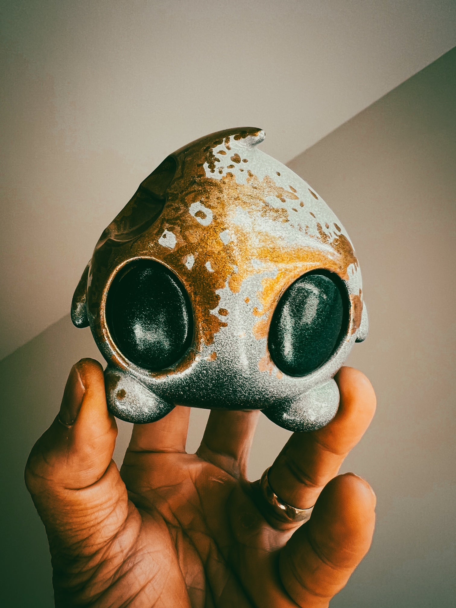 Hand holding Bite Me - Bites by Mecha Panda, a unique mixed-media art toy from Strangecat Toys, showcasing intricate metal and oval details.