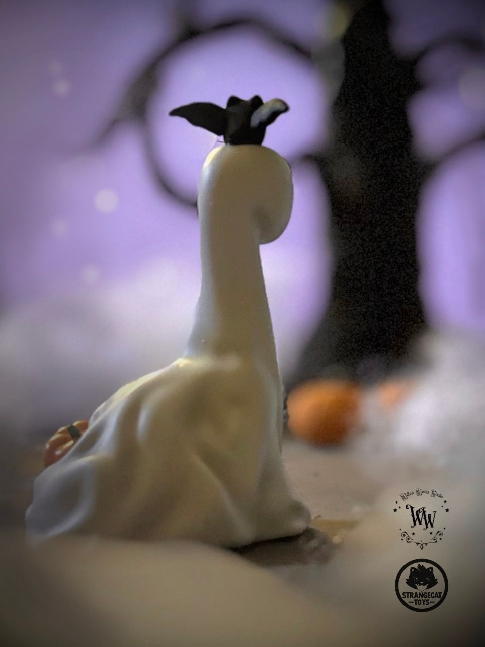 Ghost Dino by Willow Works, a 4 art toy, features a ghost sheet with black ears, set against a purple-lit backdrop with a pumpkin.