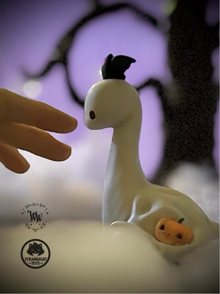 Ghost Dino by Willow Works: a white, dinosaur-like figurine with bat-wing hat and jack-o’-lantern, set in a Halloween-themed scene. Preorder, limited edition of 75.