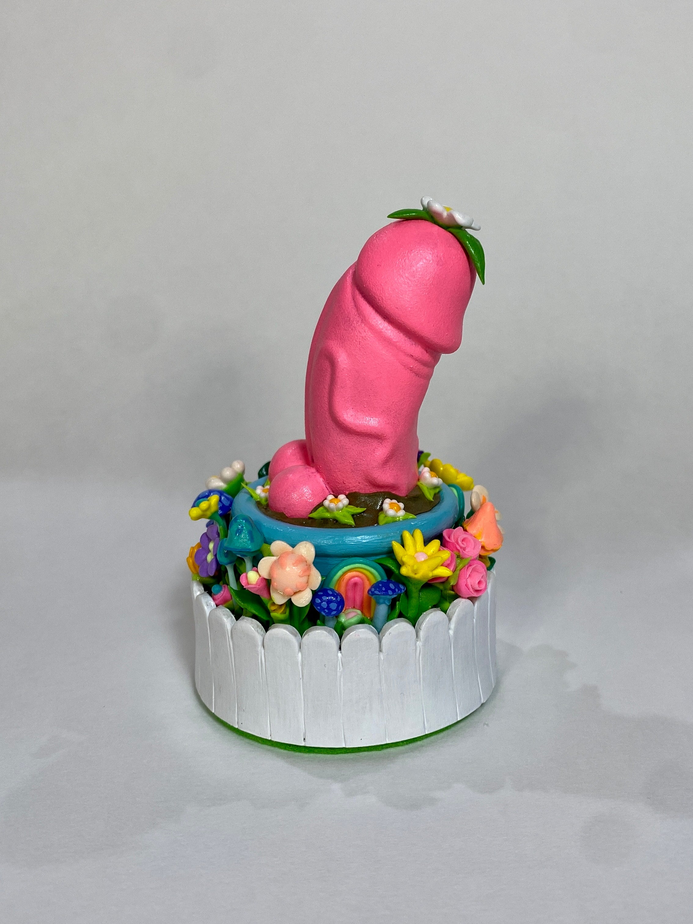 Toy cake topper with pink animal, yellow flower candy, and blue mushroom on cake.