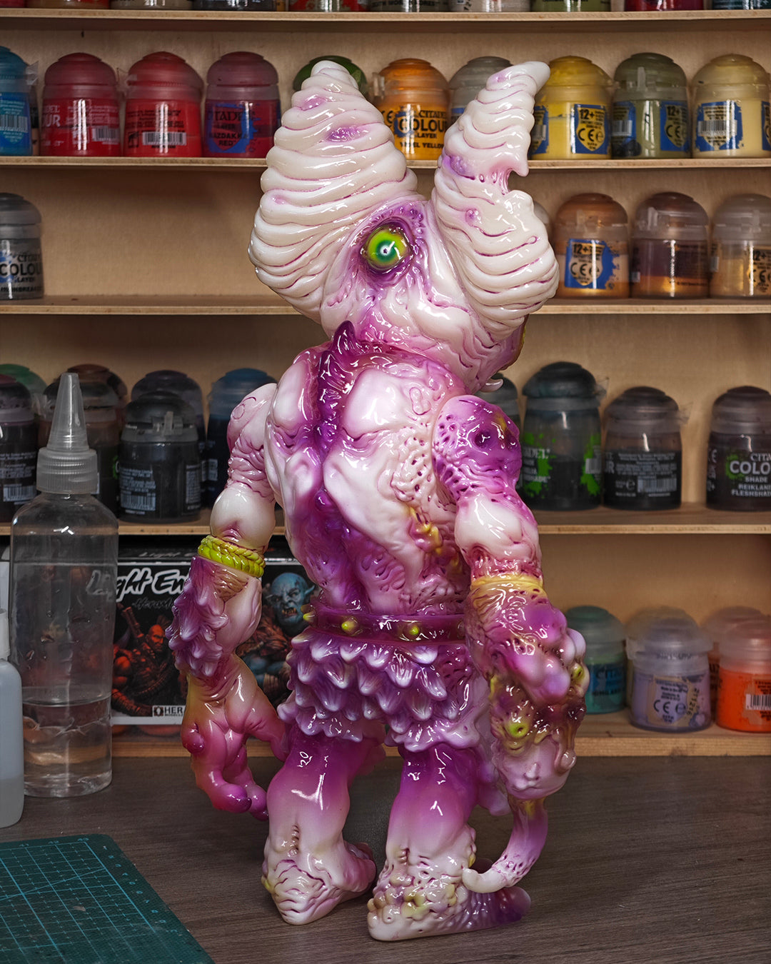 Custom-painted vinyl art toy, NPK · Poison Veil Ver. & Jack o’ Lantern III by KCB Toy, displayed with hobbyist tools and paints on a workbench.