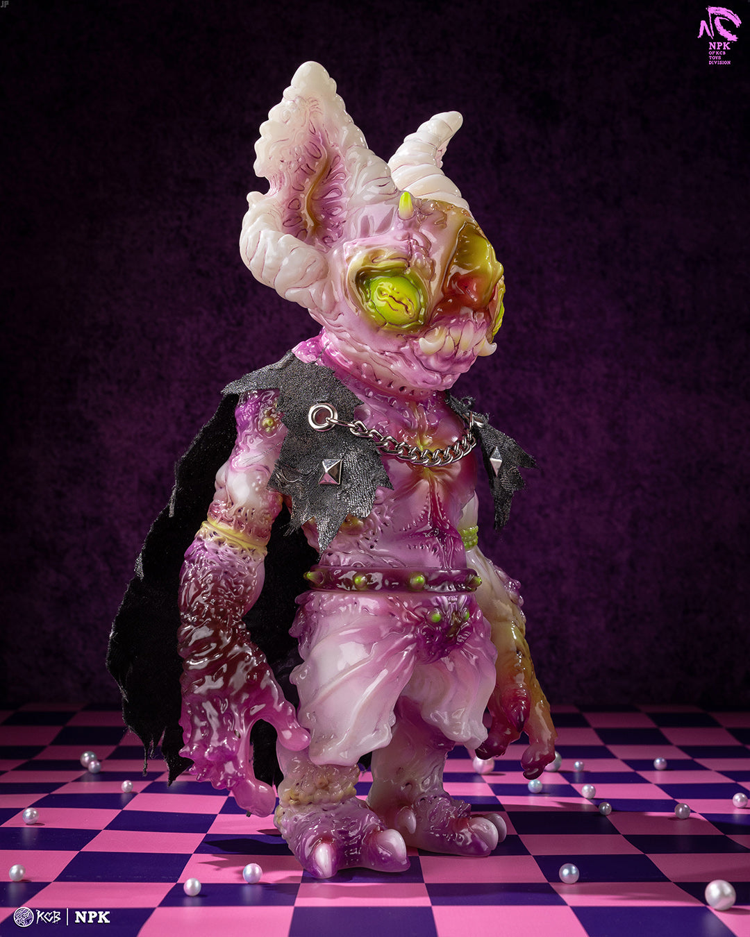 NPK · Poison Veil Ver. art-toy: translucent mutant creature with cape and green belt, standing on a checkerboard floor with scattered beads. Preorder from Strangecat Toys.