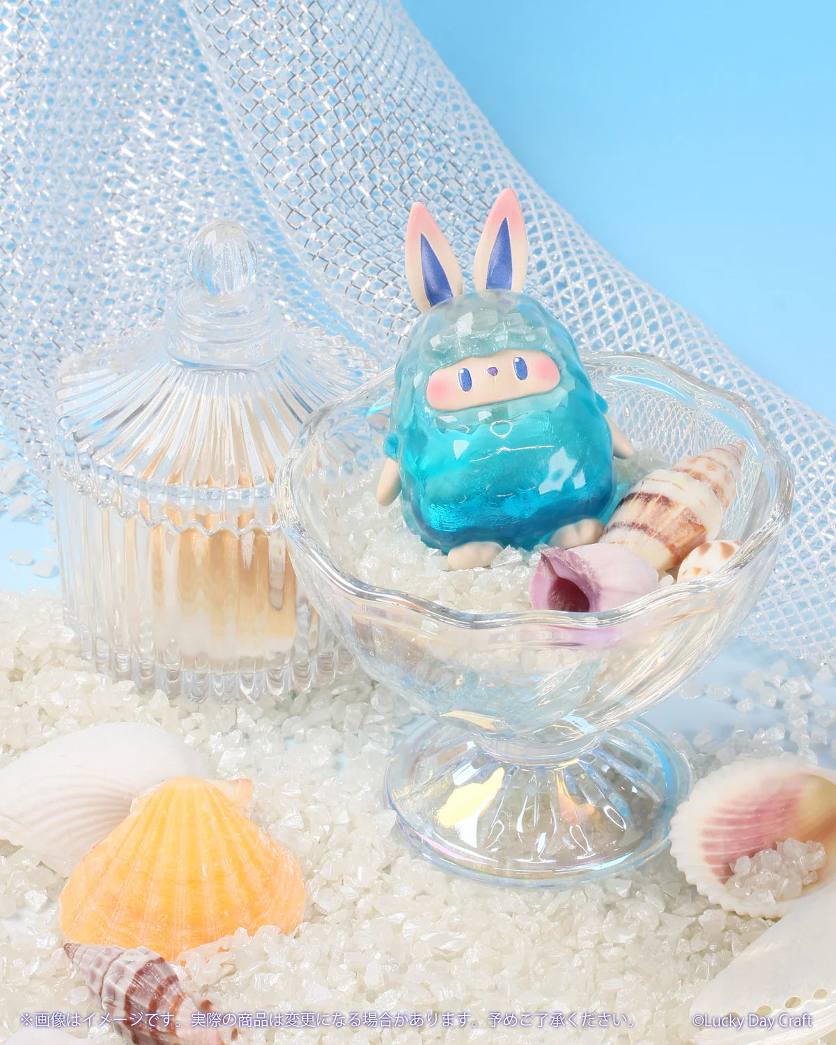 BUNNY MAY FIGURE MASCOT Gacha Series: A transparent blue resin bunny-eared figure in a glass bowl with shells, part of Strangecat Toys' blind box collection.