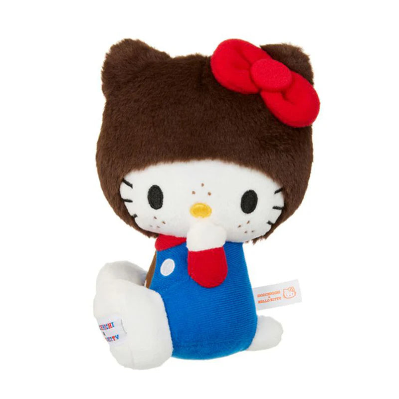 Hello Kitty x Monchhichi Overalls Plush, a 7 plush toy, features Hello Kitty in a fuzzy bear hood, blue outfit, and signature red bow, holding paw to mouth.