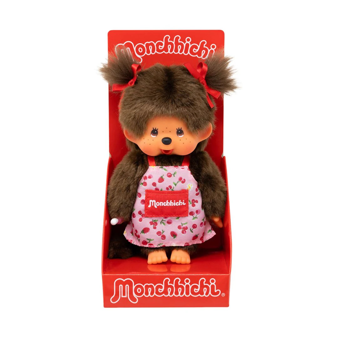 Monchhichi Girl - Flower Apron Plush Toy in branded packaging, featuring soft fur, vinyl face, pigtails, and a floral apron with Monchhichi logo, perfect for collectors.