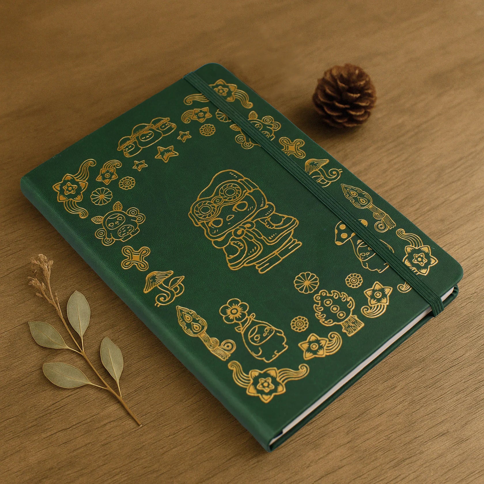 Notebook - POKO by Pucky: A5 dark-green hardcover with gold-stamped whimsical designs, held by elastic. Preorder for January 2026.