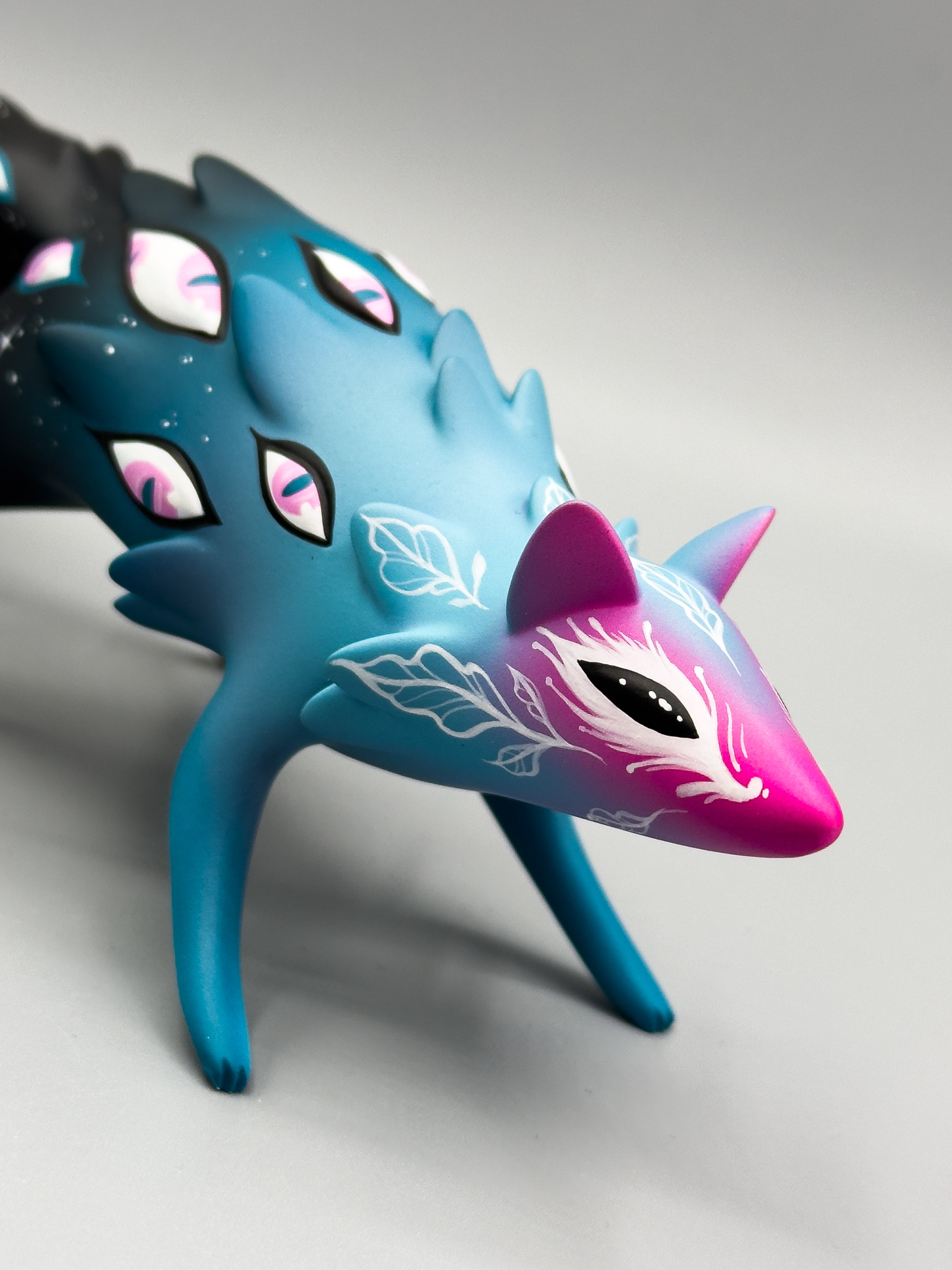Cosmyrr figurine by Tomodachi Island x Faunwood, featuring vivid blue-magenta hues, eye motifs, and delicate vine designs, crafted from high-grade resin.