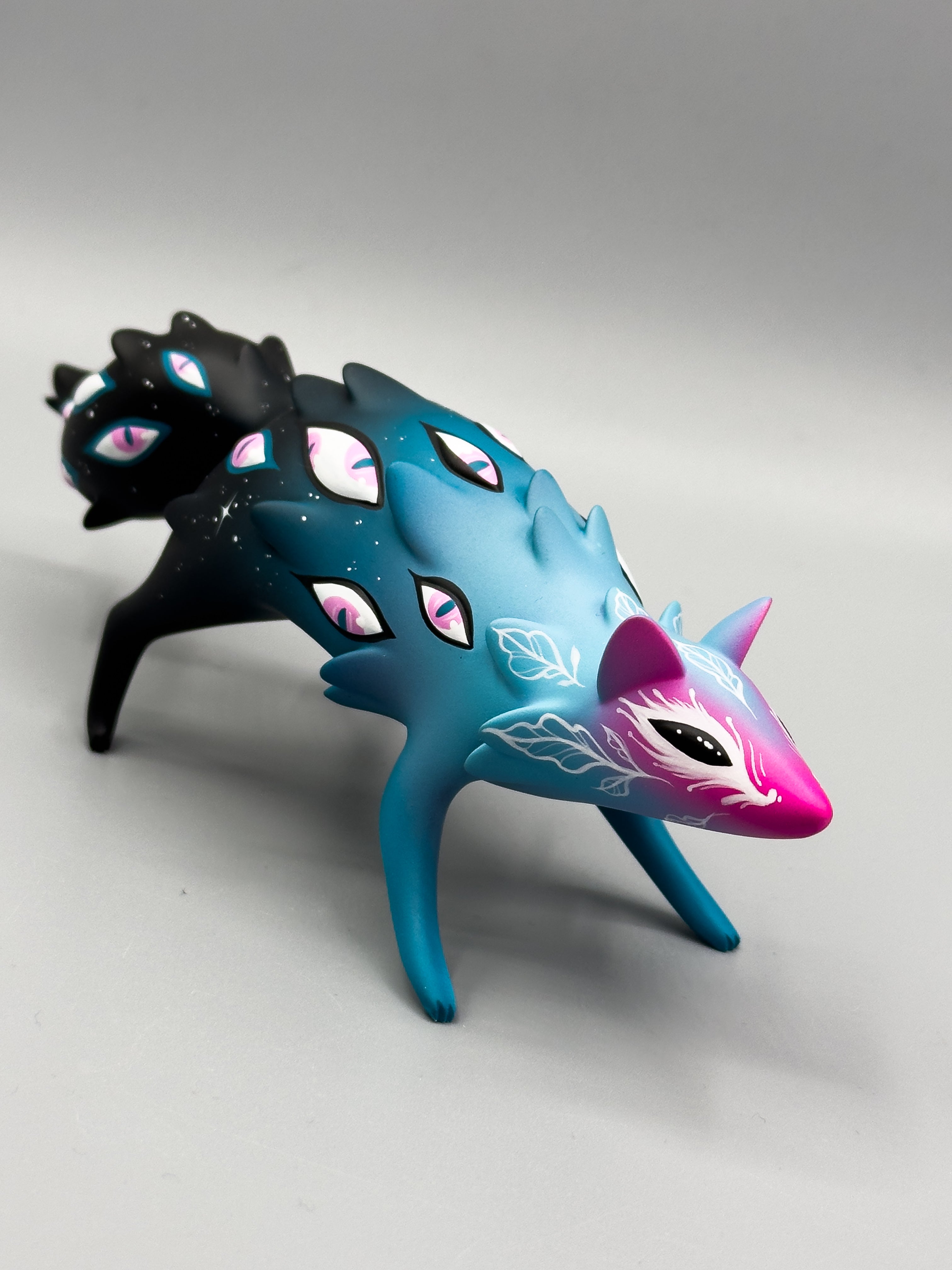 Cosmyrr by Tomodachi Island x Faunwood: A 10cm resin fox-like figurine, featuring teal and magenta with painted eyes and vine motifs.