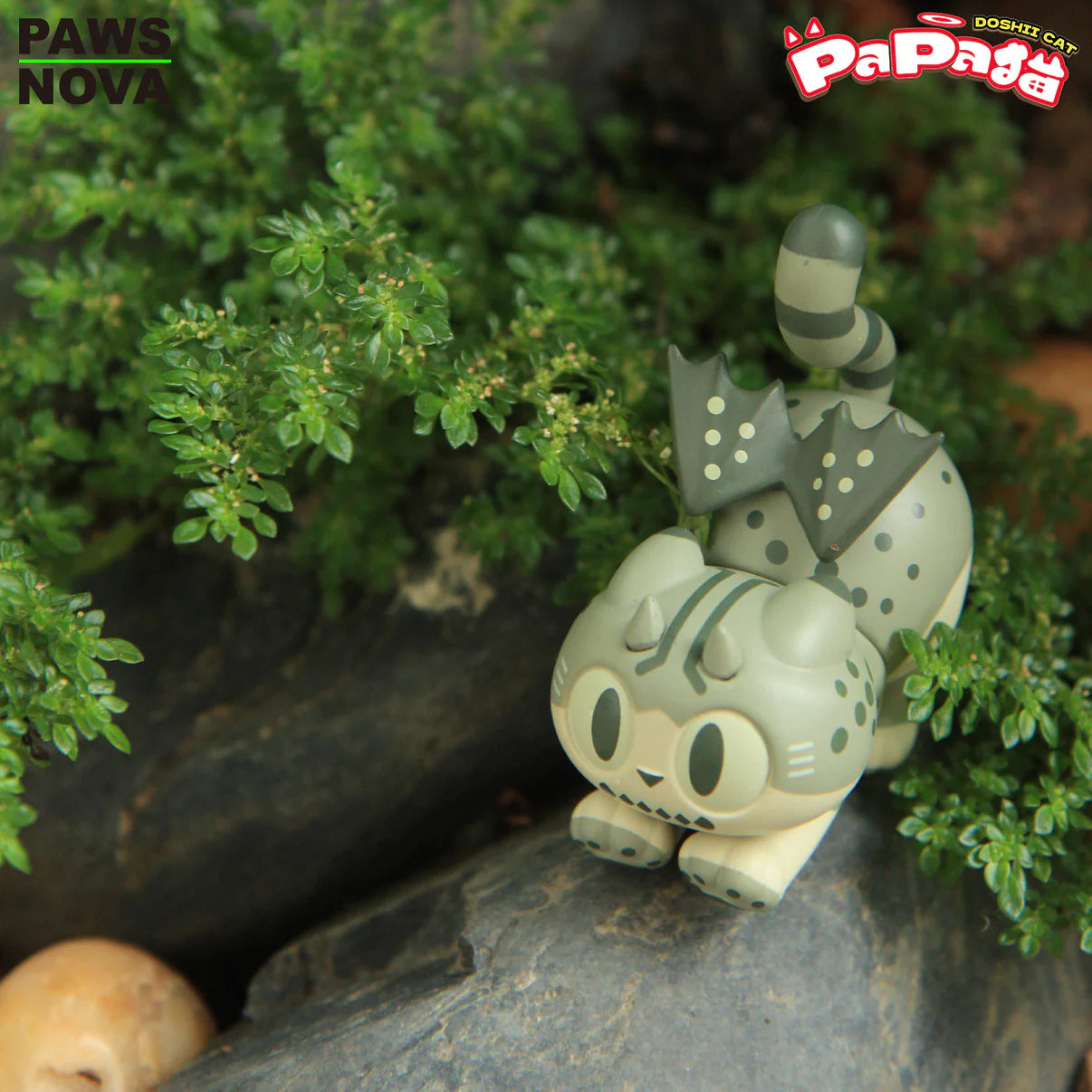 TROUBLE CREW PAPA CAT BLIND BOX collectible: A stylized cat-dragon vinyl figure with wings, horns, and cartoon eyes, nestled in greenery.