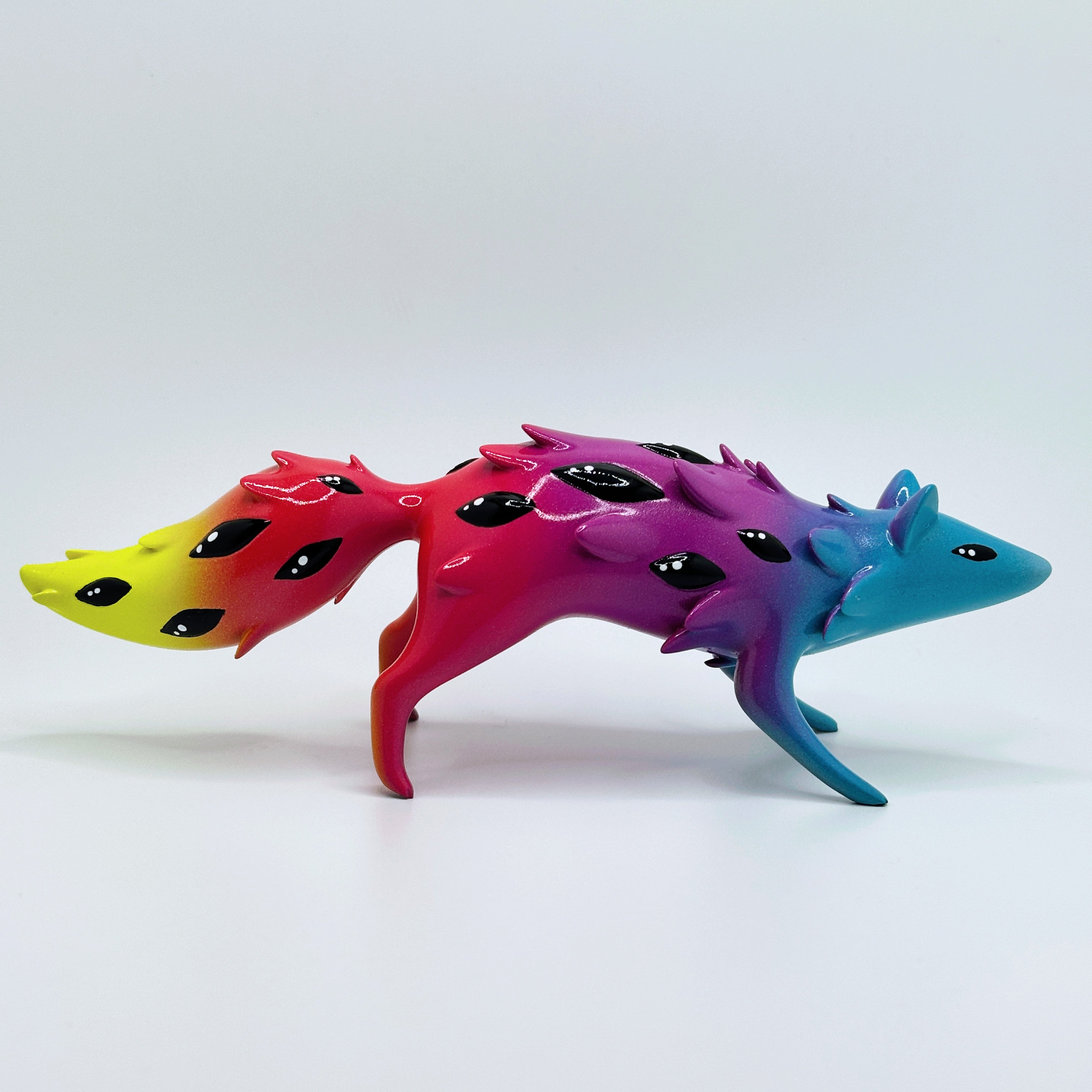 Sunset Oracle figurine by FixedTempleToys x Faunwood, a resin piece with rainbow gradient and teardrop spots, featuring flame-like protrusions.