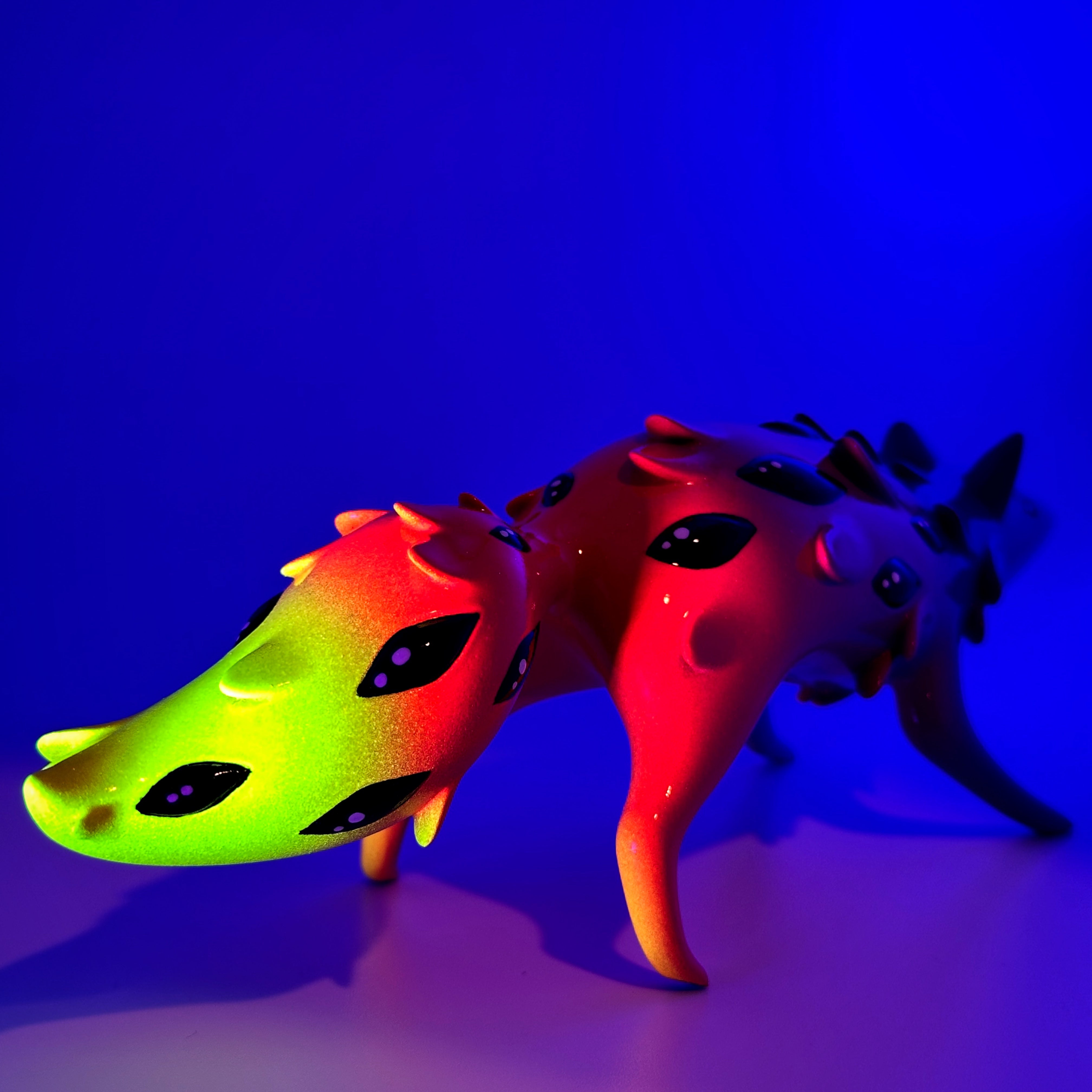 Sunset Oracle by FixedTempleToys x Faunwood: A glossy, abstract creature sculpture with gradient colors, featuring stubby legs, spikes, and eye-like markings. 10cm resin art toy.