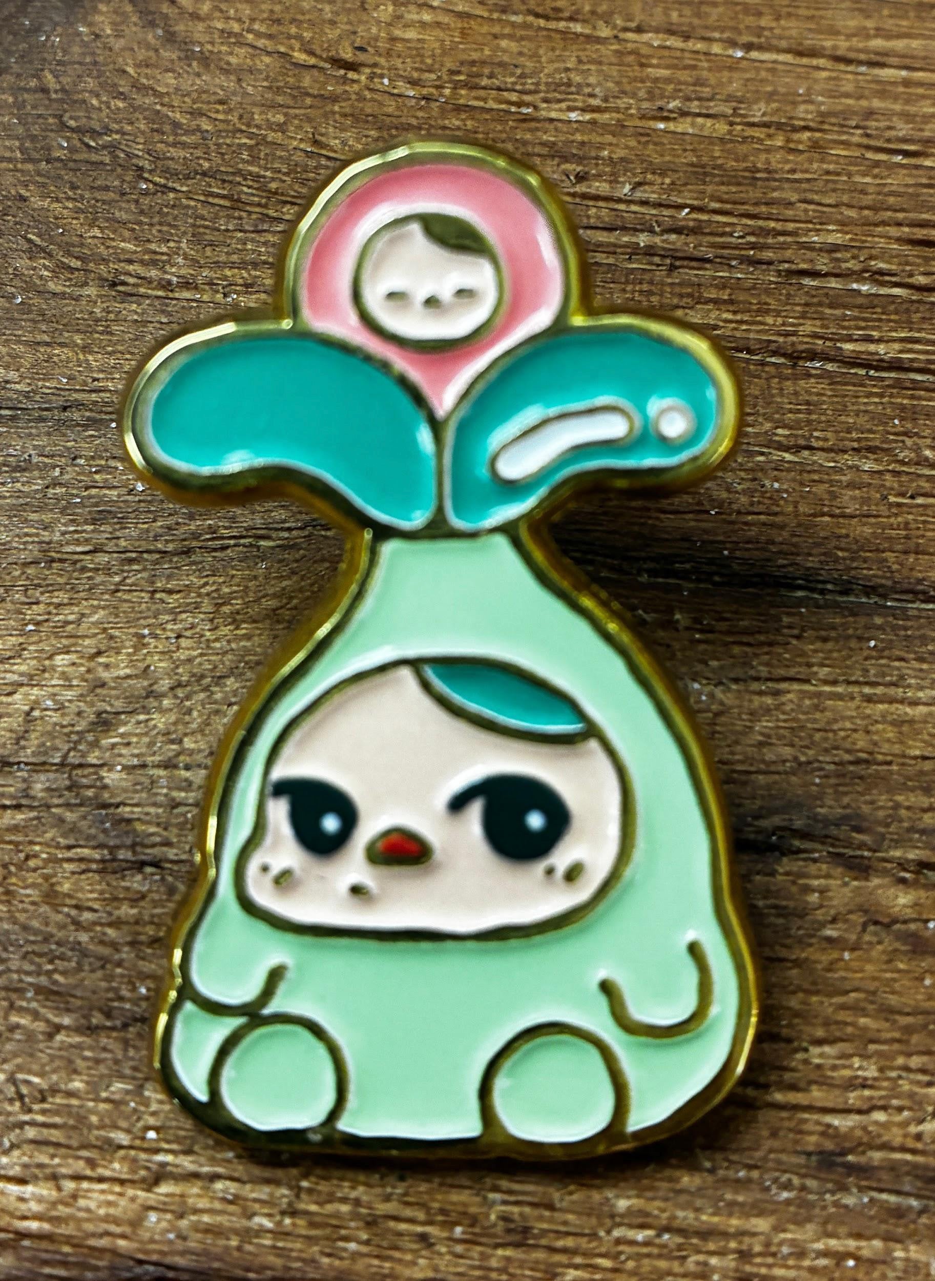 Bloom Pins by Pucky: A pastel enamel pin featuring a chibi plant-themed character with big eyes and a smiling face, perfect for collectors.