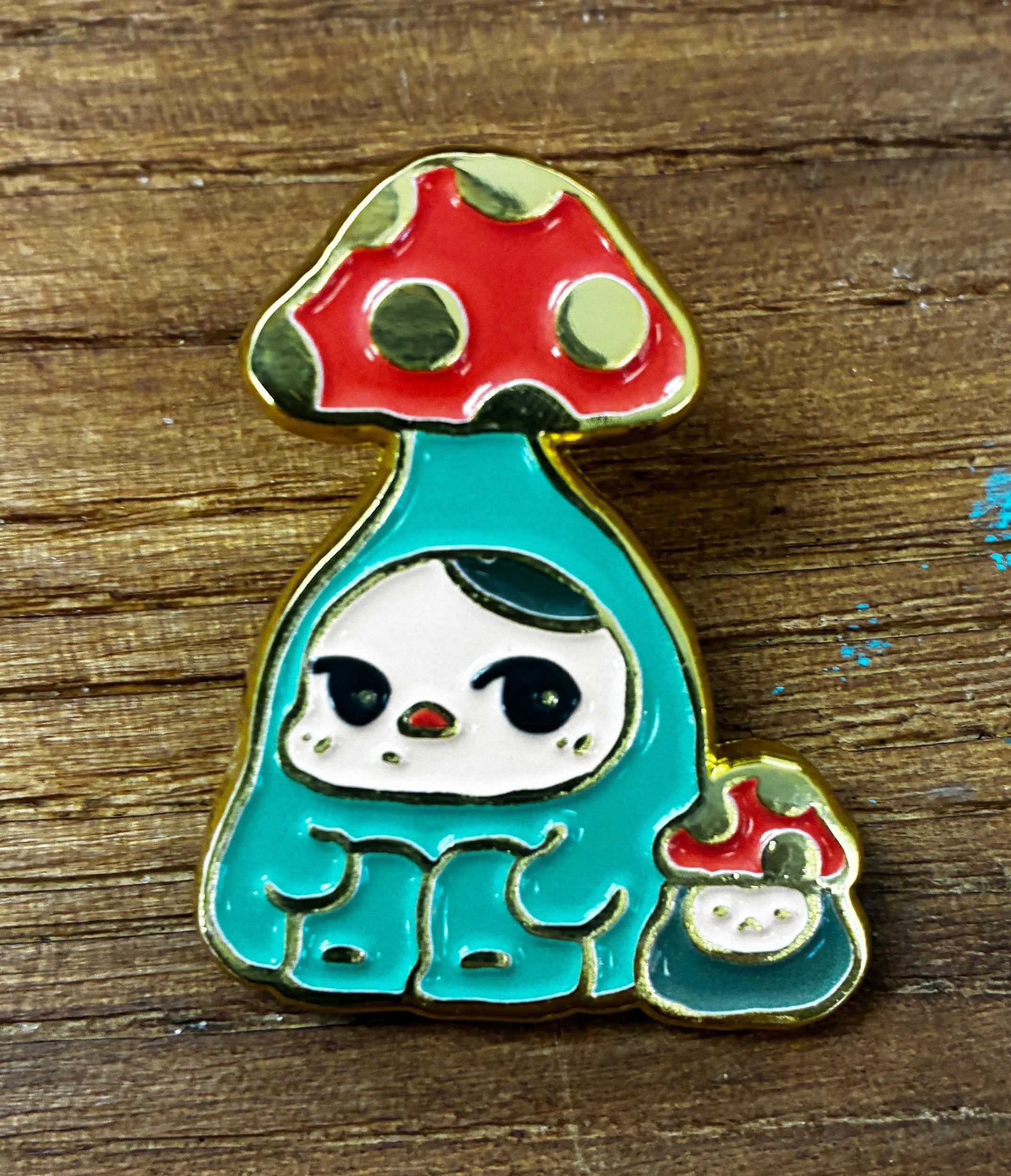 Bloom Pins by Pucky: A whimsical enamel pin featuring a character in a mushroom costume with a smaller mushroom companion, perfect for art toy enthusiasts.