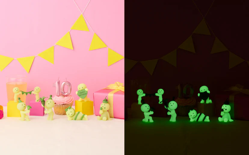 SMISKI Birthday Series: Day and night views of glow-in-the-dark figurines celebrating around a cupcake, featuring various playful poses and props.