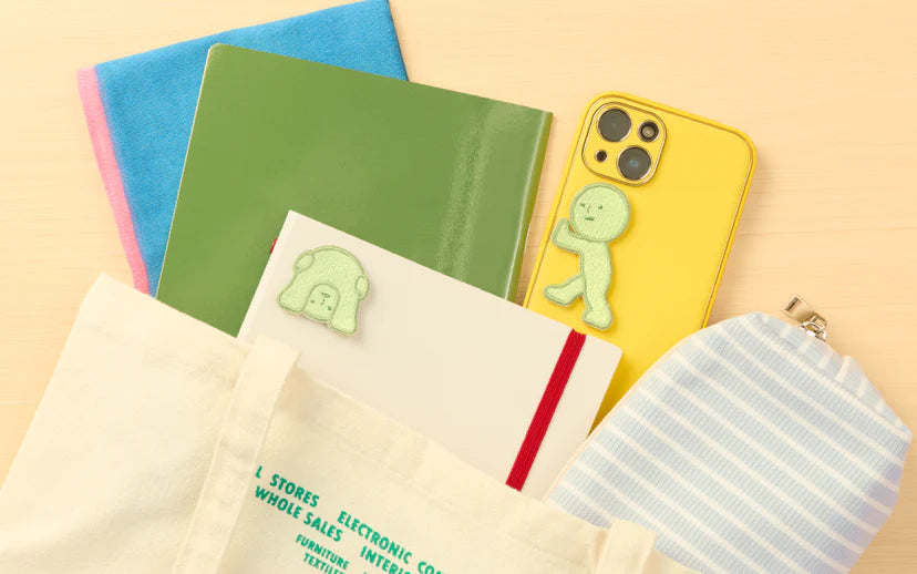 SMISKI Embroidery Sticker Vol. 2 features green felt patches on a smartphone and notebook, ideal for personalizing items with style and character.