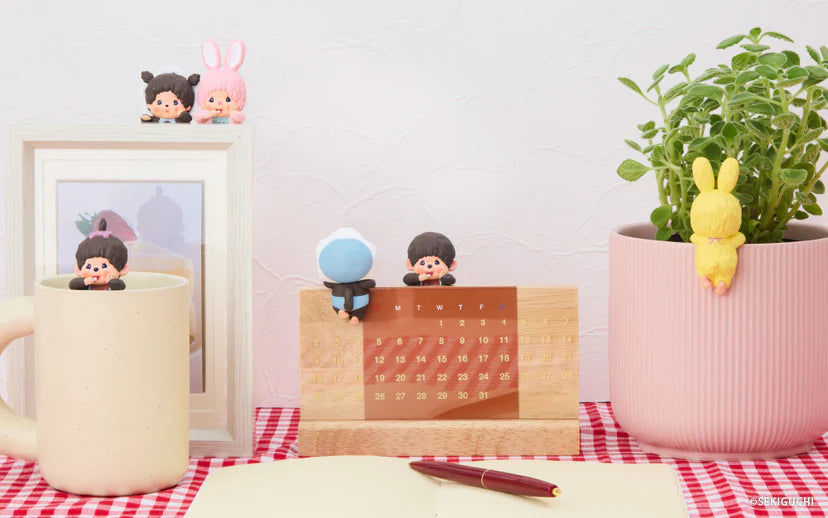 Monchhichi HIPPERS figurines playfully interact with a mug, calendar, and planter, showcasing adorable decoration possibilities for everyday objects.