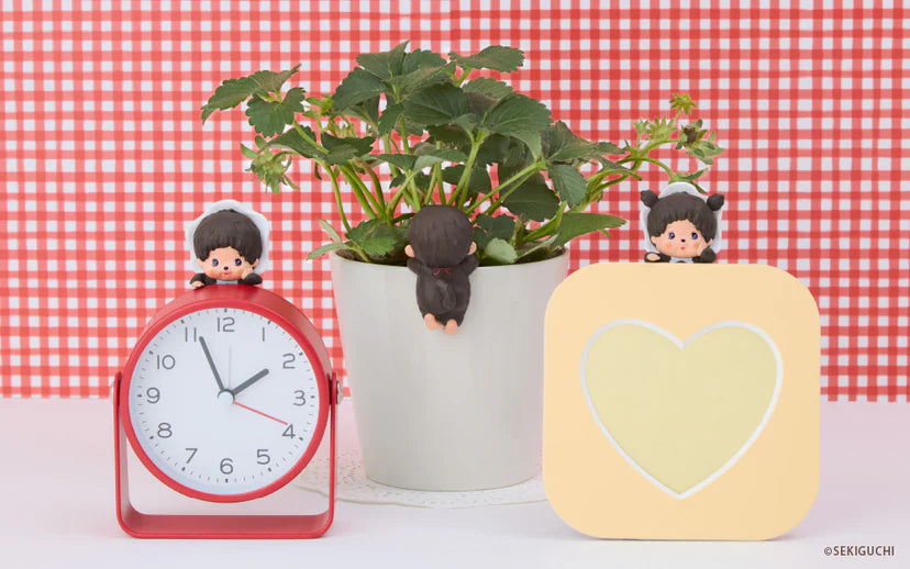 Monchhichi HIPPERS figures adorning a clock, plant pot, and card holder, showcasing their playful, versatile attachment on everyday items.