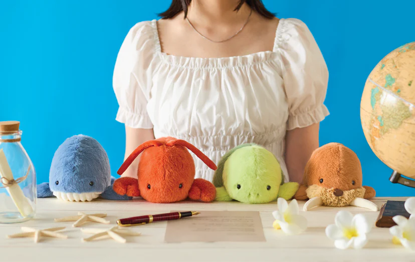 Posture Pal - Marine plush toys: whale, lobster, turtle, and otter on table; playful nautical theme, promoting comfort and proper posture at desks.