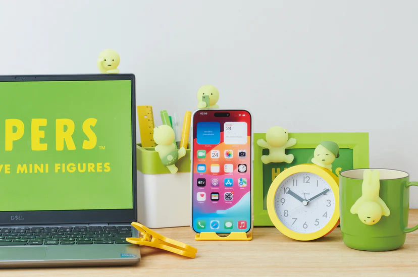 Smiski HIPPERS clinging to a laptop and smartphone on a desk, showcasing their versatility and glowing feature for decorative use on gadgets.