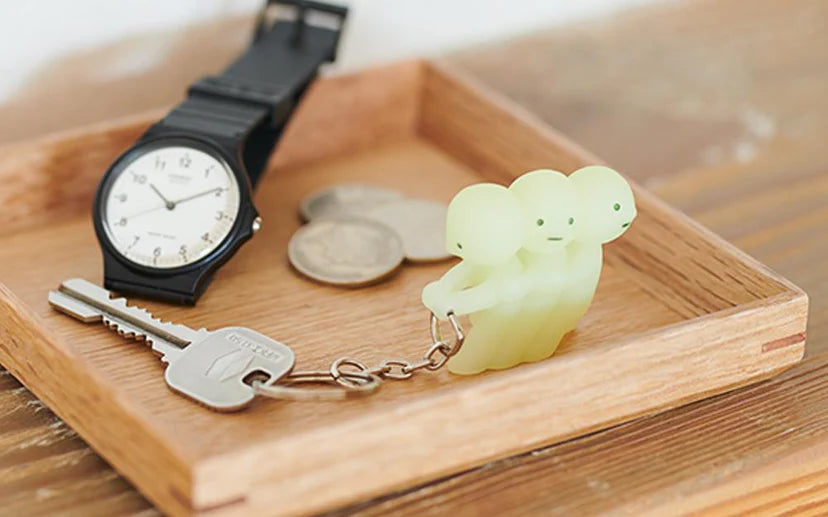 Smiski Keychain and a watch on a wooden tray. The keychain glows in the dark, helping to locate keys easily.