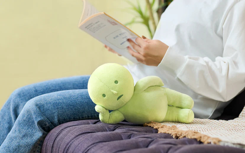 Person reading on a couch with a SMISKI Plush beside them, showcasing its soft texture and comforting feel, perfect for added comfort during relaxation.